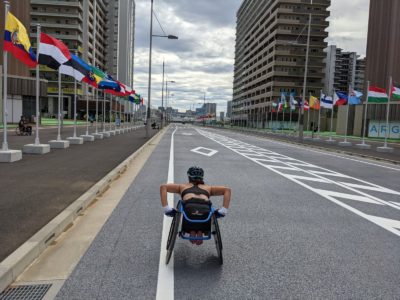 Eine junge Frau fährt mit ihrem Rennrollstuhl auf einer Straße bei den Paralympics in Japan